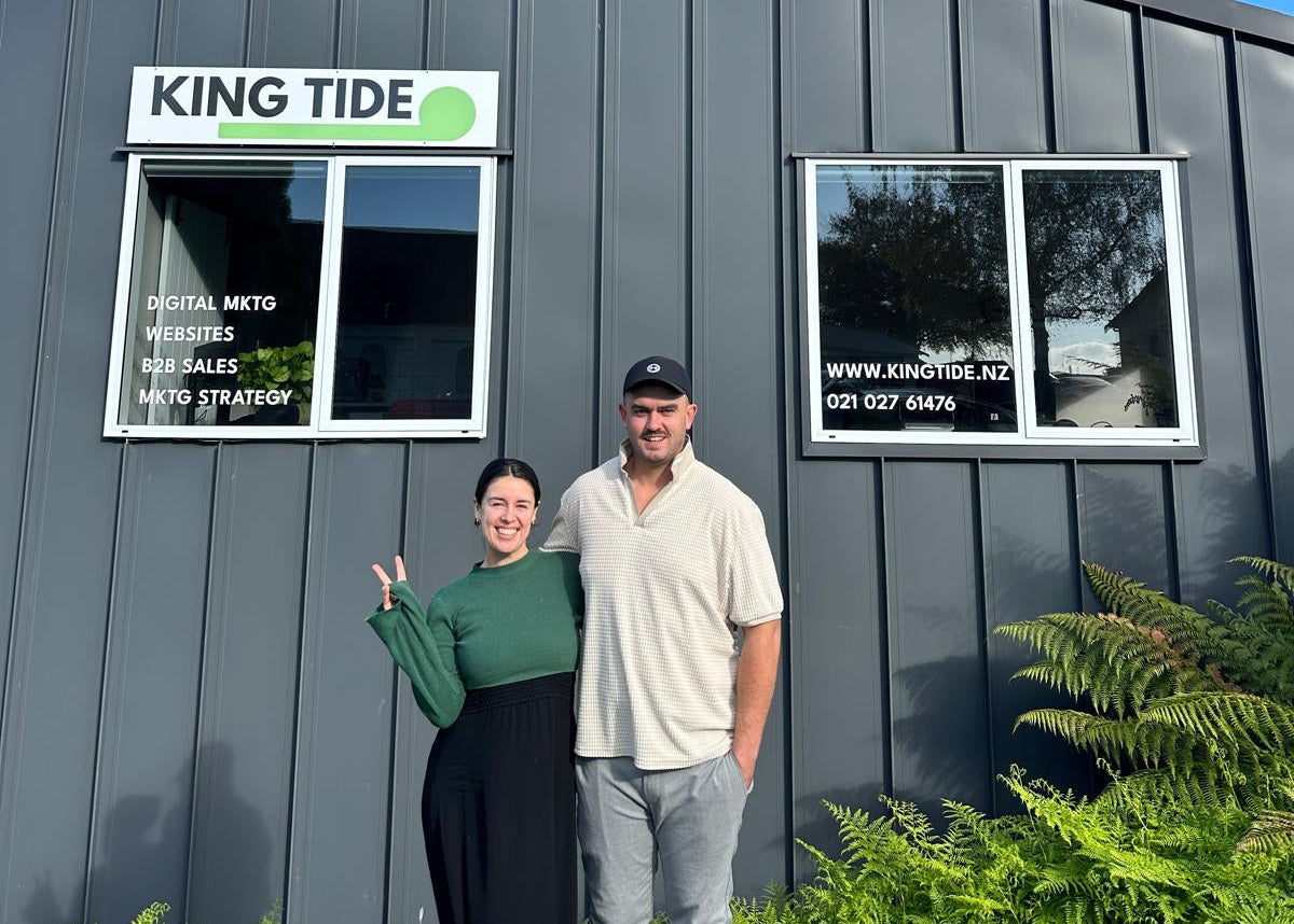 Louis and Steph standing in front of a building with 'KING TIDE' signage on a clear day.